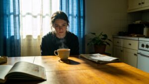Person sitting at kitchen table in quiet distress representing everyday experience of the global mental health crisis