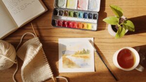 Woman painting watercolours at kitchen table representing creative hobbies for adults