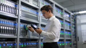 A network hardware specialist verifying optical communication lines on a localized server rack inside a modern data facility.
