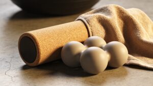 A premium cork foam roller and silicone mobility massage tools resting on a clean studio floor.