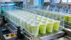 An advanced automated washing facility cleaning reusable plastic event cups on a fast-moving conveyor belt system.