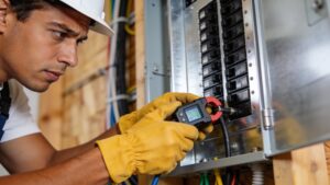 An electrician installing smart current transformer sensor clamps inside a home electrical breaker box.