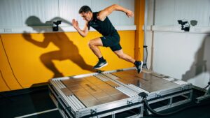 An elite athlete executing a precision jump analysis on digital force plates within a sports science lab.