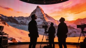 An elite film crew operating within a massive curved LED volume displaying a highly realistic mountain environment.