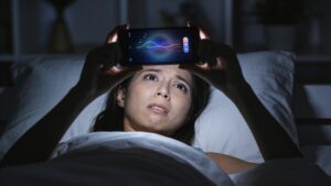 Person lying awake anxiously checking a sleep tracking app at night"