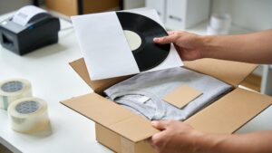 Hands packing fan merchandise into a shipping mailer for a direct-to-fan order"