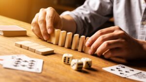 Hands arranging game pieces, dice and cards on a table.