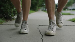 Two people walking briskly side by side on a neighborhood sidewalk.