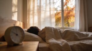 Alt text: Person sleeping in a calm bedroom with soft autumn morning light.