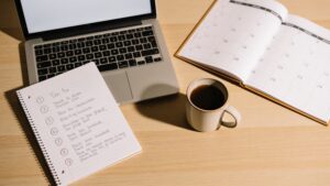 Desk with a checklist, laptop, and calendar for planning purchases.